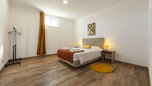 A bedroom with a bed, bedside tables, a floor lamp, a window with curtains, and a painting on the wall.