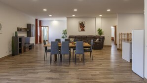Ein modernes Wohnzimmer mit Essbereich, Holzboden und Einbauleuchten.