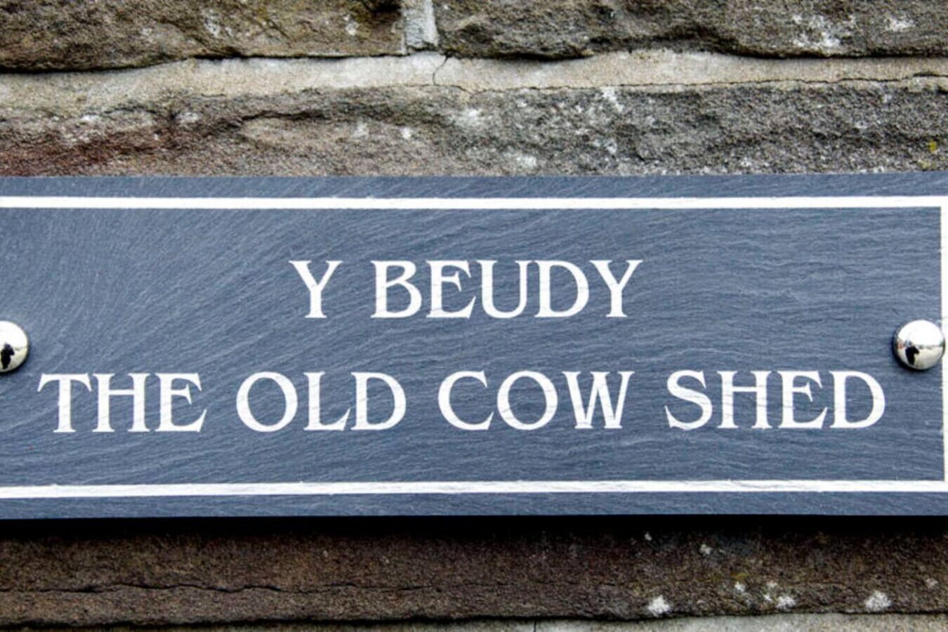 Liitutaulusta tehty kyltti, jossa lukee: ”Y BEUDY THE OLD COW SHED”.