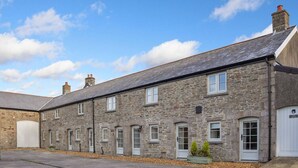 A stone building with multiple windows and doors, a flat roof, and a paved area in front. - 3 Bed Cottage • Parking • Ideal for Work Trips (Pontardawe)