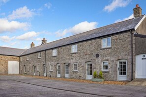 A stone building with multiple windows and doors, a flat roof, and a paved area in front. - 3 Bed Cottage • Parking • Ideal for Work Trips (Pontardawe)