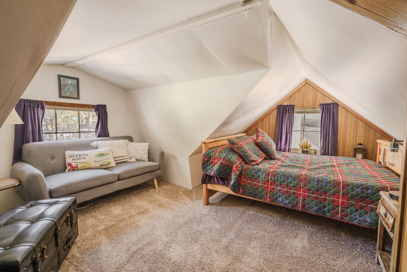 Ein gemütliches Schlafzimmer im Dachgeschoss mit einem Schlafpodest, einer Couch und einem kleinen Tisch.