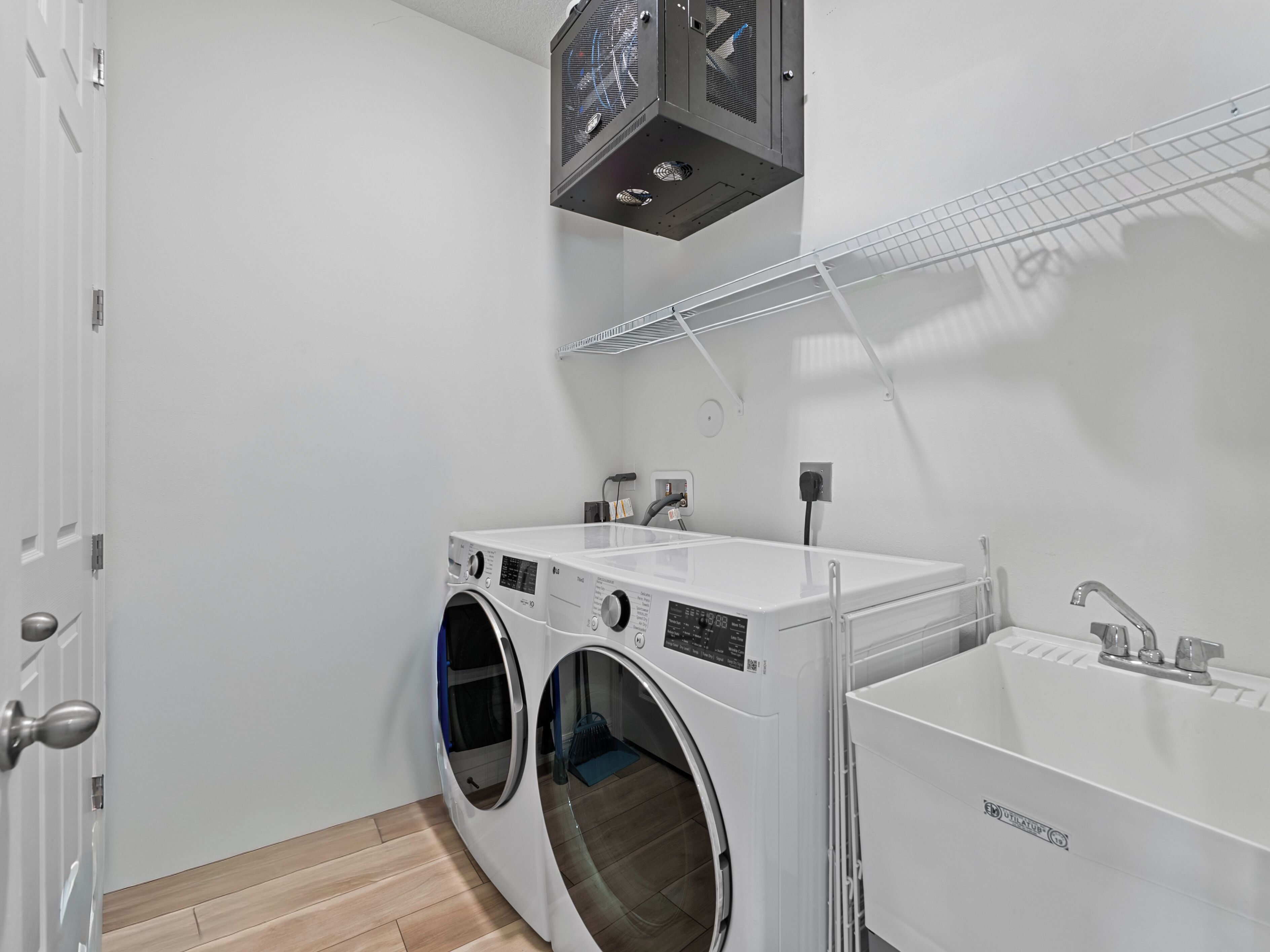 A laundry room with two front-loading washing machines, a sink, and a ceiling fan.