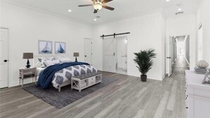 Une chambre à coucher moderne avec un lit, des tables de chevet, un ventilateur de plafond et une plante en pot.