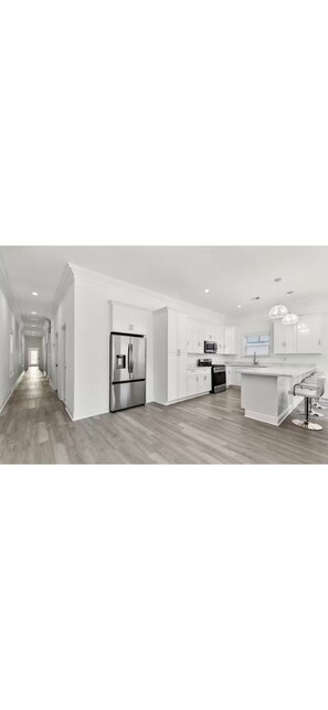 A modern kitchen with white cabinets, a stainless steel refrigerator, and a central island. - Spacious 4-bedroom house in perfect New Orleans with AC (New Orleans)