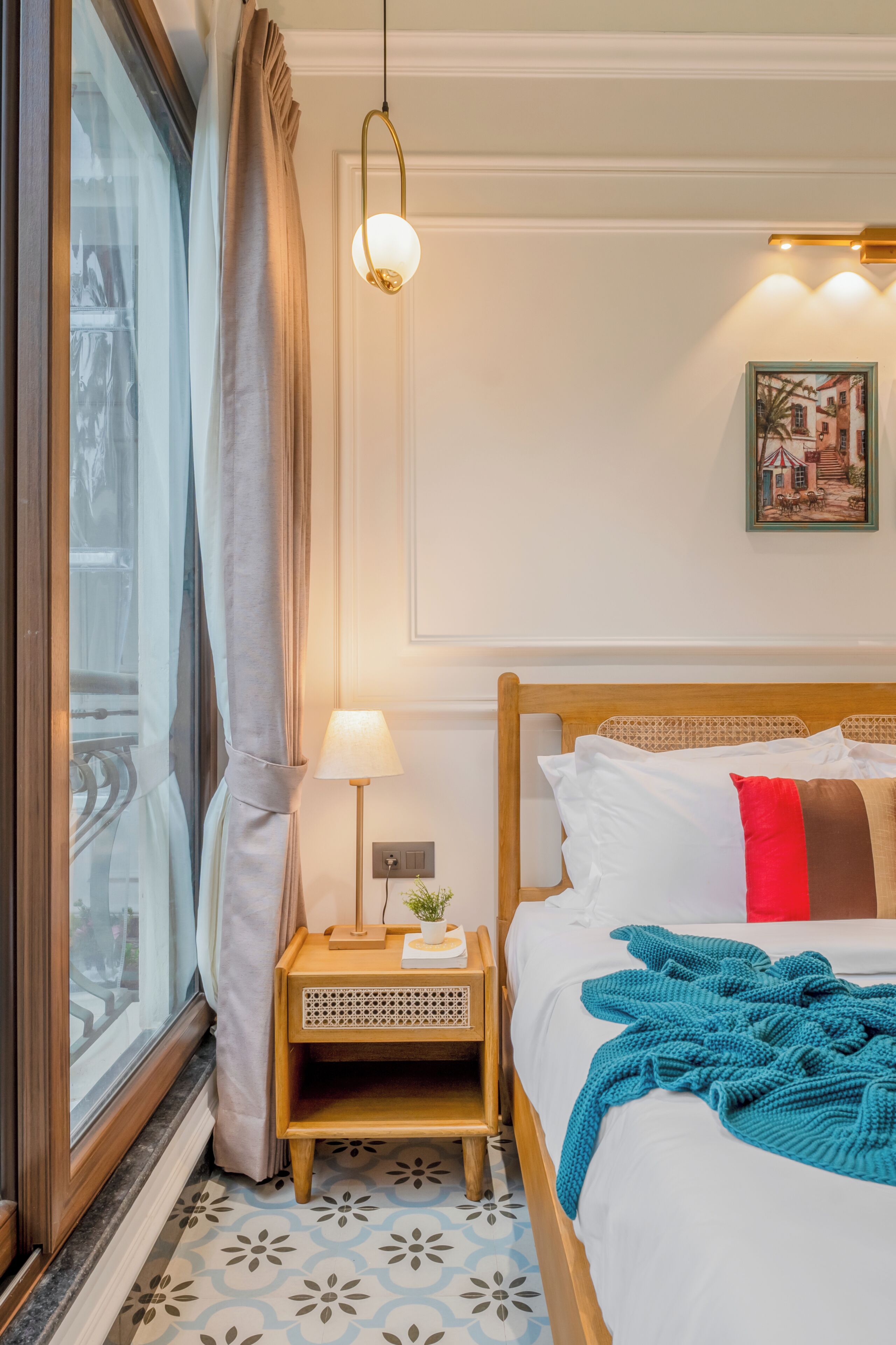 Habitación de hotel impecable con cama, mesita de noche, lámpara y ventana con cortinas.