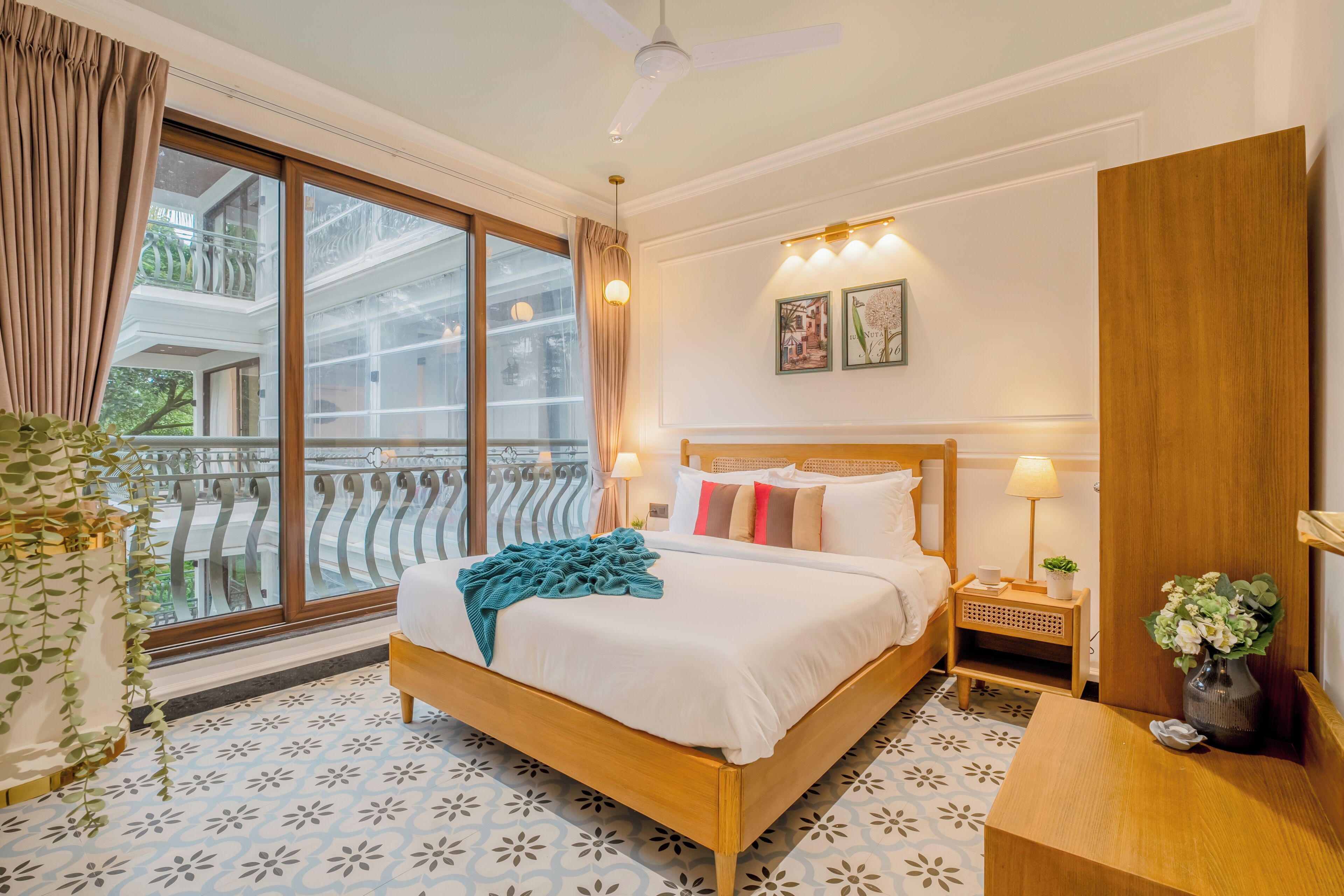 A bedroom with a large window, a bed, a bedside table, and a nightstand.