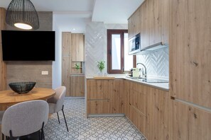 Une cuisine moderne avec des meubles en bois, un téléviseur à écran plat, une table à manger avec des chaises et un sol à motifs.