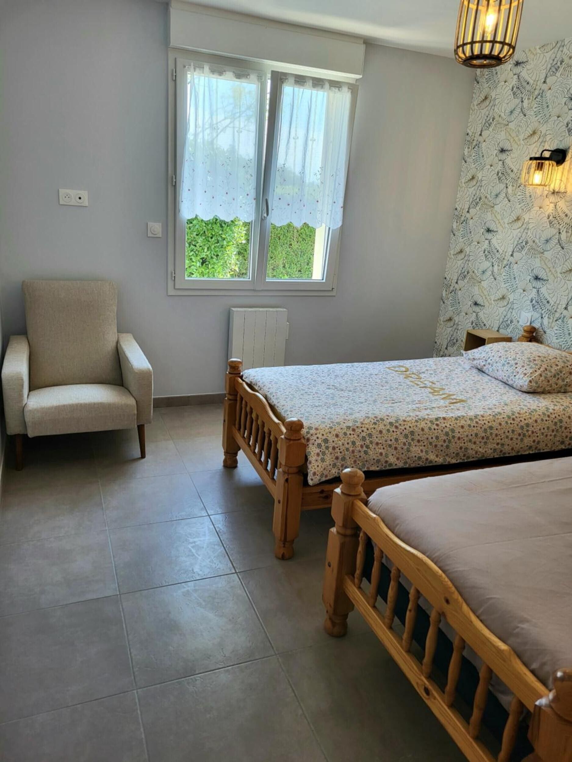 A bedroom with a bed, a chair, a window with curtains, and a radiator.