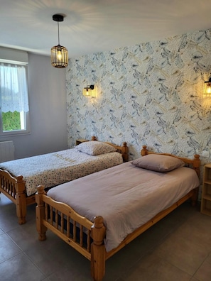 Ein Schlafzimmer mit zwei Holzbett, einem gemusterten Wandteppich und einem Fenster mit Blick.