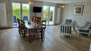 A dining area with a wooden table and chairs, a television, and a painting on the wall. - Gîte Cadet Rousselle: private terrace, private garden & Wi-Fi in Lessay (Lessay)