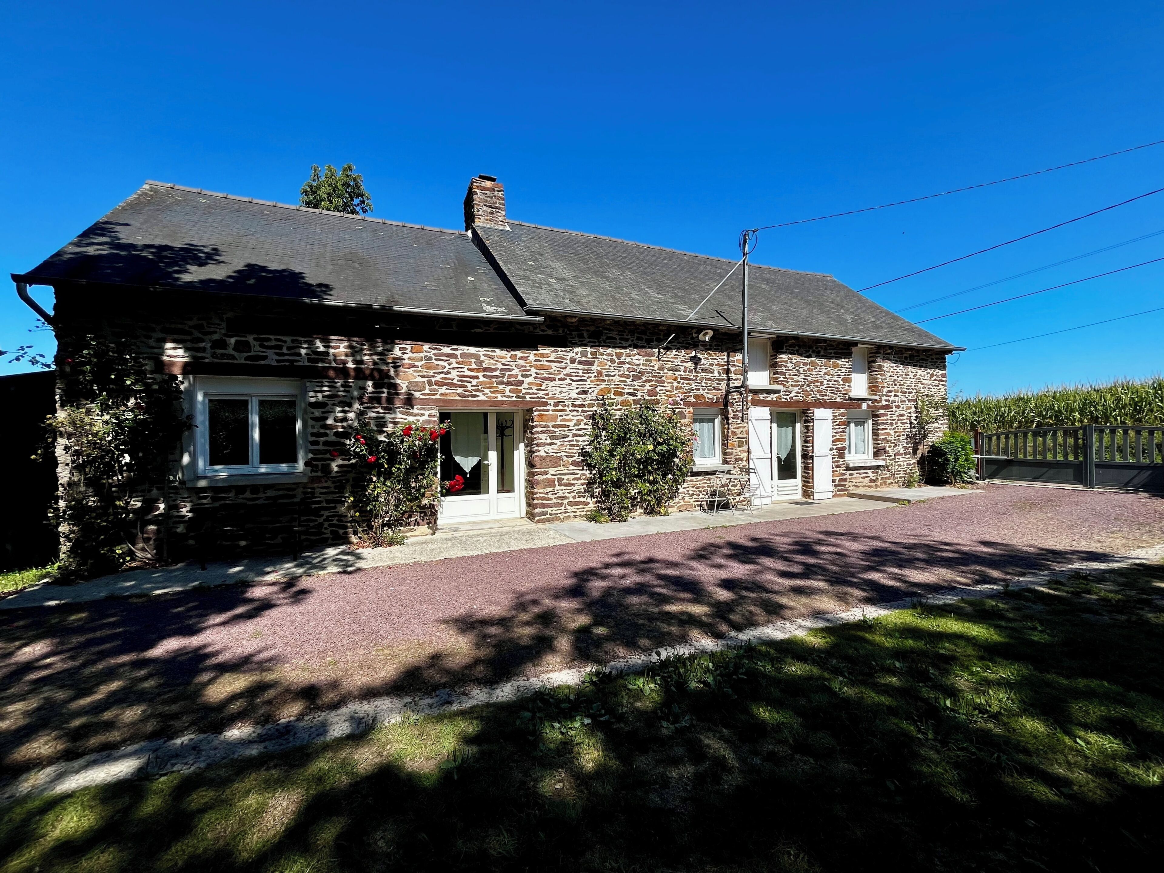 Un bâtiment en pierre avec un toit en pente, une porte d’entrée et un petit porche.