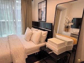 Ein Hotelzimmer mit Bett, Nachttisch, Buch, Spiegel und Fernseher.