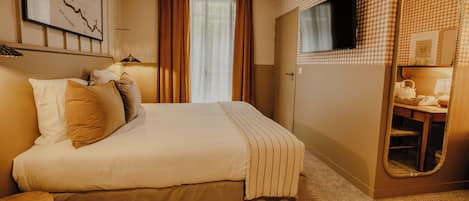 Habitación de hotel con cama, espejo, televisor y un mapa enmarcado en la pared.