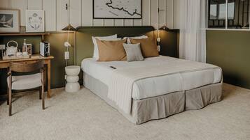 A neatly arranged bedroom with a bed, bedside lamps, a desk with a chair, and a wall-mounted map.
