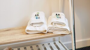 Dos toallas blancas dobladas con aceites esenciales sobre una estante de madera en una habitación de hotel.