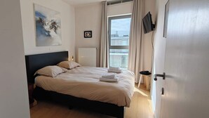 Una camera da letto con un letto, un termosifone, una finestra con tende e un quadro appeso al muro.