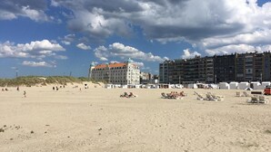 Una spiaggia con un grande edificio con una cupola e un moderno grattacielo sullo sfondo.