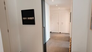 Un corridoio con una porta, un quadro appeso al muro e un pavimento piastrellato.