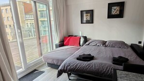 Ein modernes Schlafzimmer mit Bett, Sofa und einem großen Fenster.