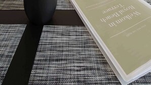 Eine moderne Küche mit weißen Schränken, einer schwarzen Uhr und einem Blumentopf auf dem Tisch.