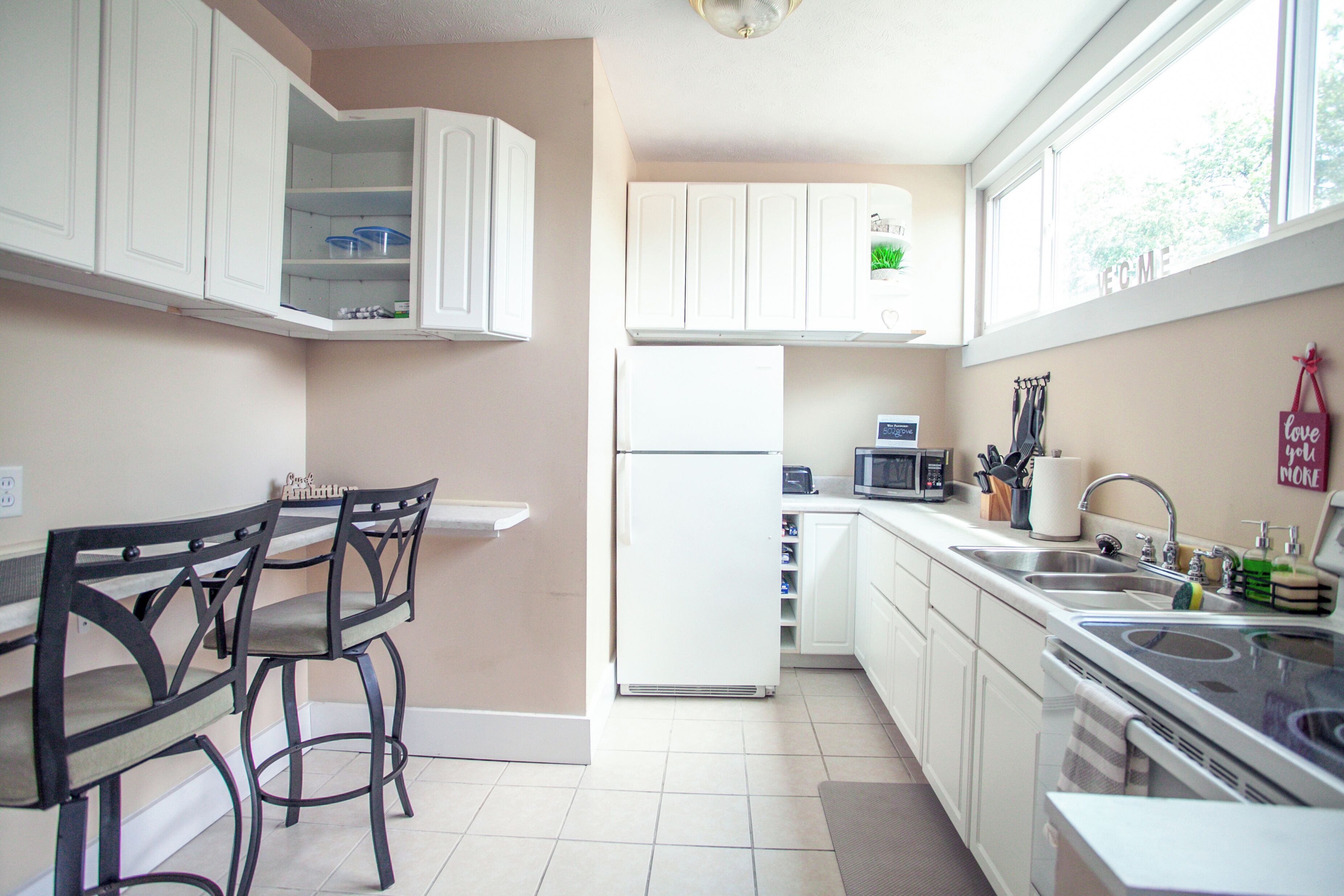 A kitchen with white cabinets, a refrigerator, a microwave, and a sink.