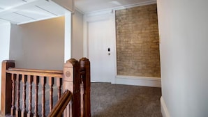 A staircase with wooden balusters, a white door, and a brick wall.