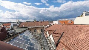 A rooftop with a glass skylight, red-tiled roofs, and a clear sky. - Family Hub in Centre (Bratislava - Old Town)