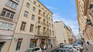 A multi-story building with balconies, a flag, and parked cars. - Family Hub in Centre (Bratislava - Old Town)