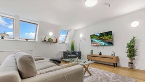 A modern living room with a sofa, a coffee table, a TV, and a plant. - Family Hub in Centre (Bratislava - Old Town)