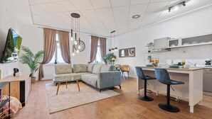 Una sala de estar moderna con un sofá, un comedor y una cocina con taburetes de bar.