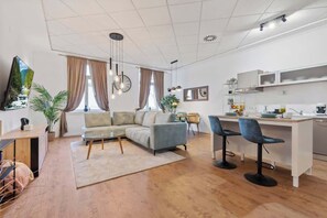 Ein modernes Wohnzimmer mit Sofa, Essbereich und Küche mit Barhocker.