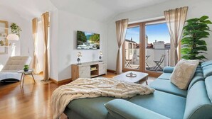A modern living room with a sofa, a coffee table, a TV, and a balcony with a view.
