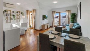 A modern living room with a dining area, a sofa, and a TV.