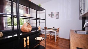 A modern kitchen with a black metal shelf unit, a dining table with chairs, and a window with curtains.