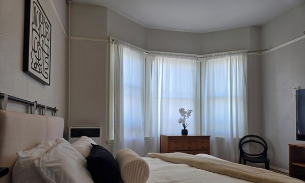 A bedroom with a bed, a nightstand, a dresser, a chair, and a television. - GORGEOUS 3 BEDROOM IN DOWNTOWN  (Oakland)