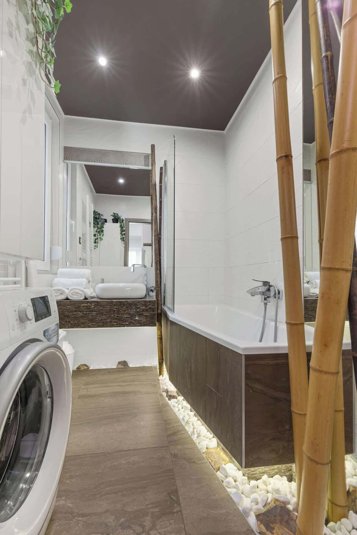 Un bagno moderno con lavatrice, vasca e uno specchio grande.