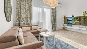 Ett modernt vardagsrum med en hörnsoffa, en platt-TV och en dekorativ hänglampa.