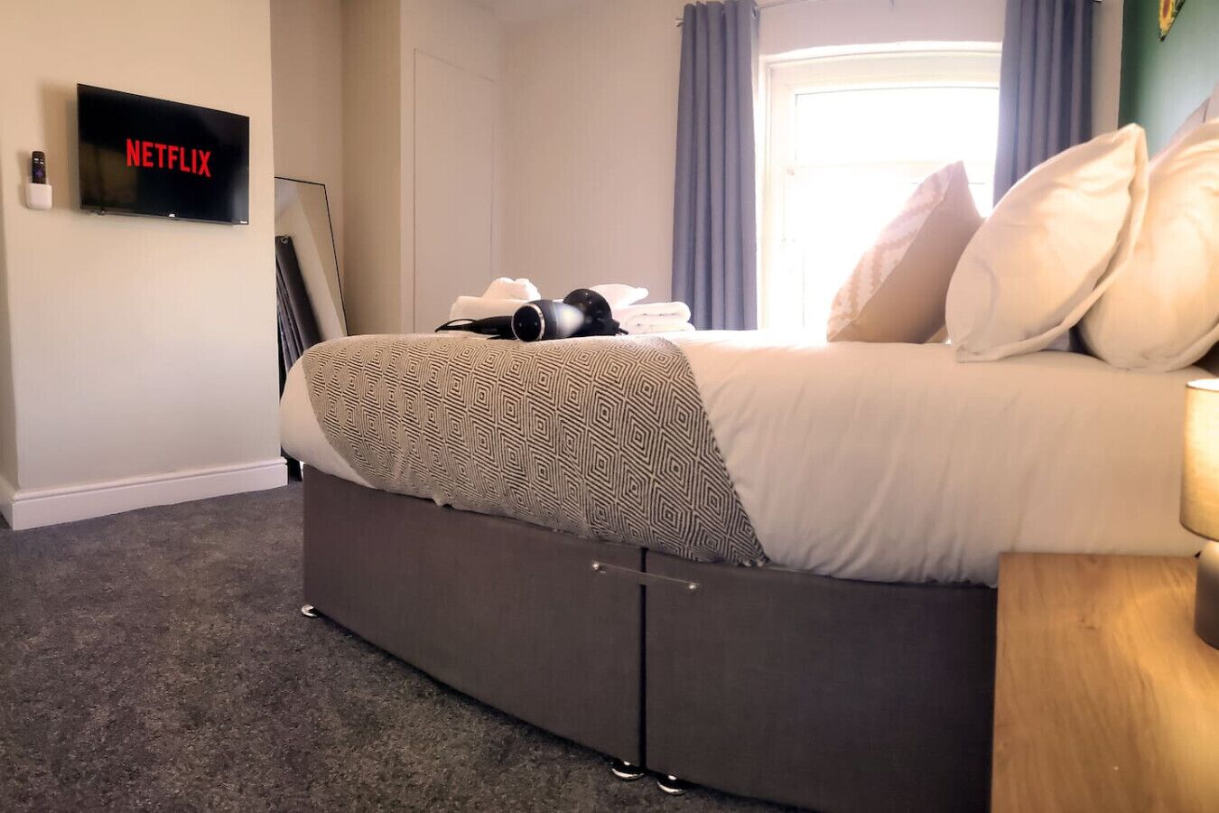 Ein Schlafzimmer mit Bett, Wand-Fernseher und einer Tür.