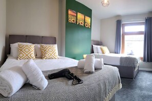 A hotel room with two beds, a green accent wall, and a window with curtains. - 3 Doubles • Sleeps 8 • Ideal for Work Crews (Neath Port Talbot)