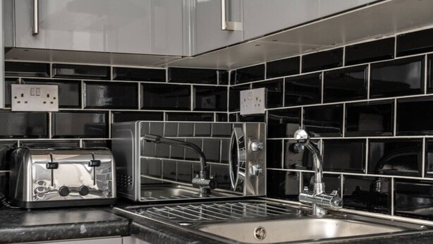 A modern kitchen with a built-in toaster, a sink, and a stainless steel faucet.