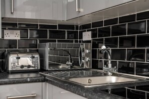 Uma cozinha moderna com torradeira embutida, pia e torneira de aço inoxidável.