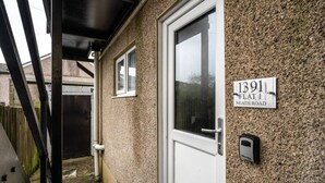 A residential house with a white door, a window, and a house number sign.