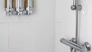 A shower with a handheld showerhead and a wall-mounted faucet.