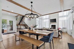 Ein geräumiger Wohnbereich mit einem Holzespeisetisch, blauen Stühlen, einer Couch und einer Treppe.