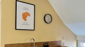 Una cocina con encimera de madera, un lavamanos negro y un reloj en la pared.