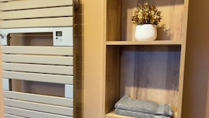 Une salle de bain moderne avec un porte-serviettes, une étagère en bois ornée d’un vase et un panier en osier.