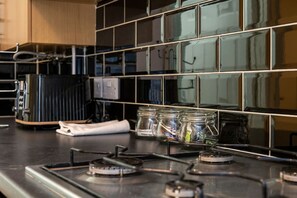 A kitchen with a stove, a coffee maker, and jars on the counter. - En-suite Flat • Kitchen • Quiet Near Shops & Bus (Swansea)