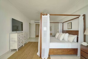 Ein Himmelsbett mit weißer Bettwäsche, einem Holz-Kopfstück und einem Baldachin.