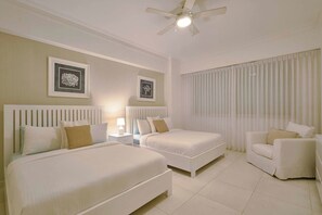 A hotel room with two beds, a chair, a nightstand, and a ceiling fan. - ®{3BR~Hemingway~Retreat}@JuanDolio+WalktoBeach+GYM (Juan Dolio)